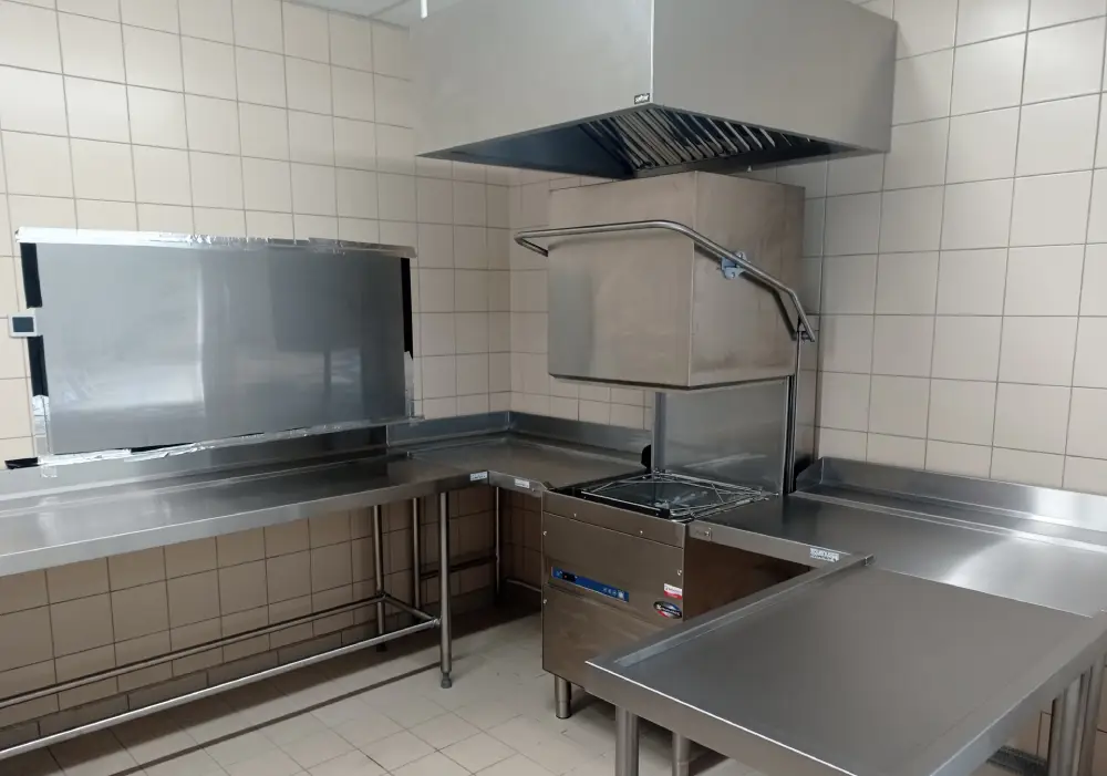 Installation de lave-vaisselle à capot professionnel par Maison Patay pour une cantine. Fabrication de mobilier inox pour une laverie vaisselle performante.