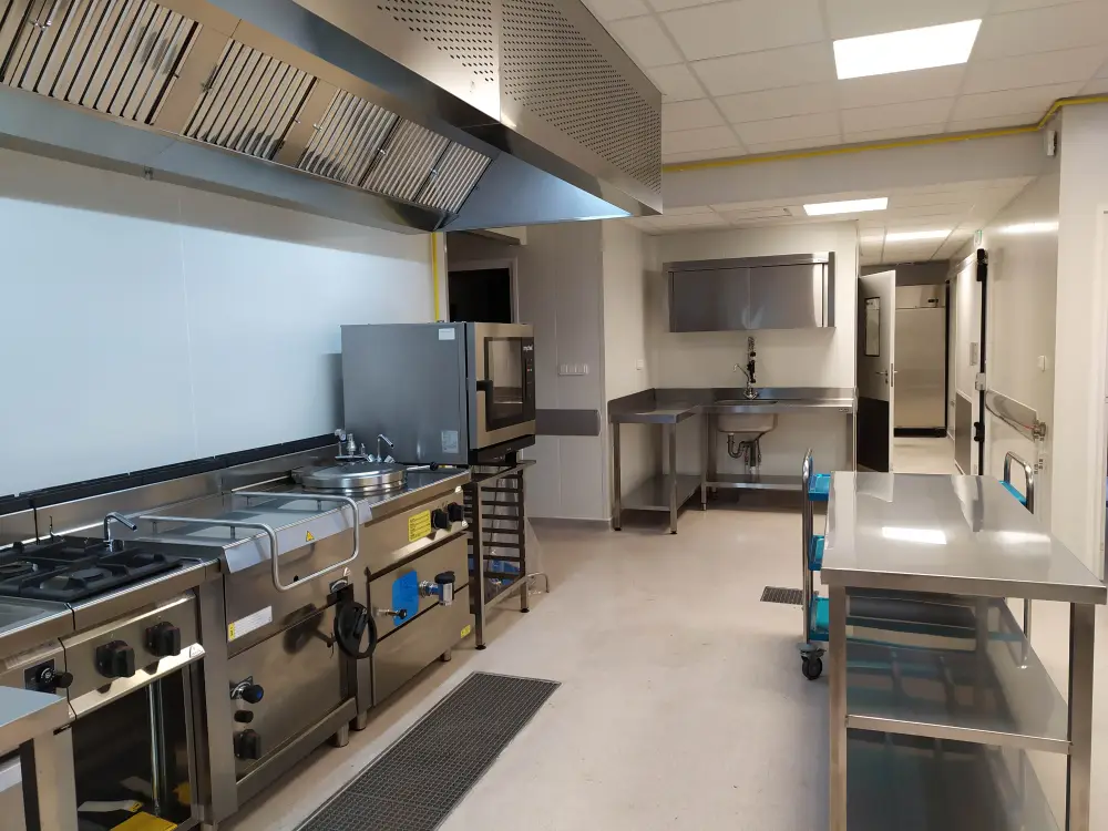 Cuisine de collectivité faite par Maison Patay : évier sur mesure, piano de cuisson professionnel, four de remise en température, mobilier inox sur mesure…