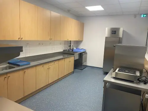 Plan de cuisine professionnelle de 20m² avec tour de préparation, frigo de collectivité, four de remise en température et batterie de cuisine inox.